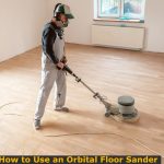 Worker operating floor orbital sander to to hardwood flooring.